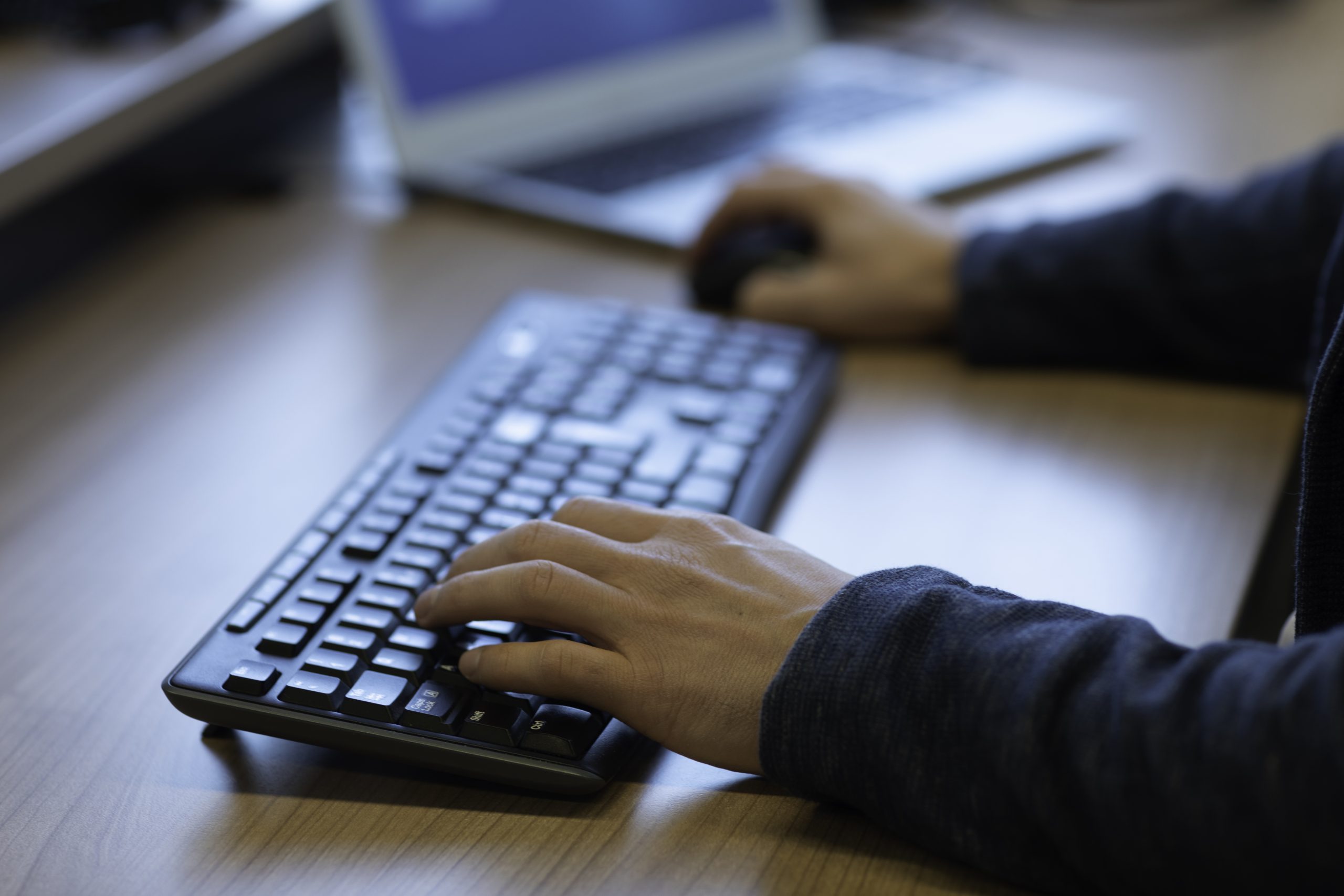 A person handling a keyboard and mouse in front of a computer screen.